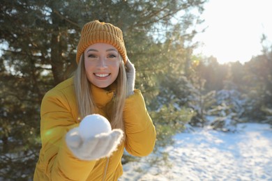 Photo of Woman holding snowball outdoors on winter day, space for text