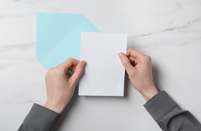 Photo of Woman with blank card at marble table, top view. Space for text