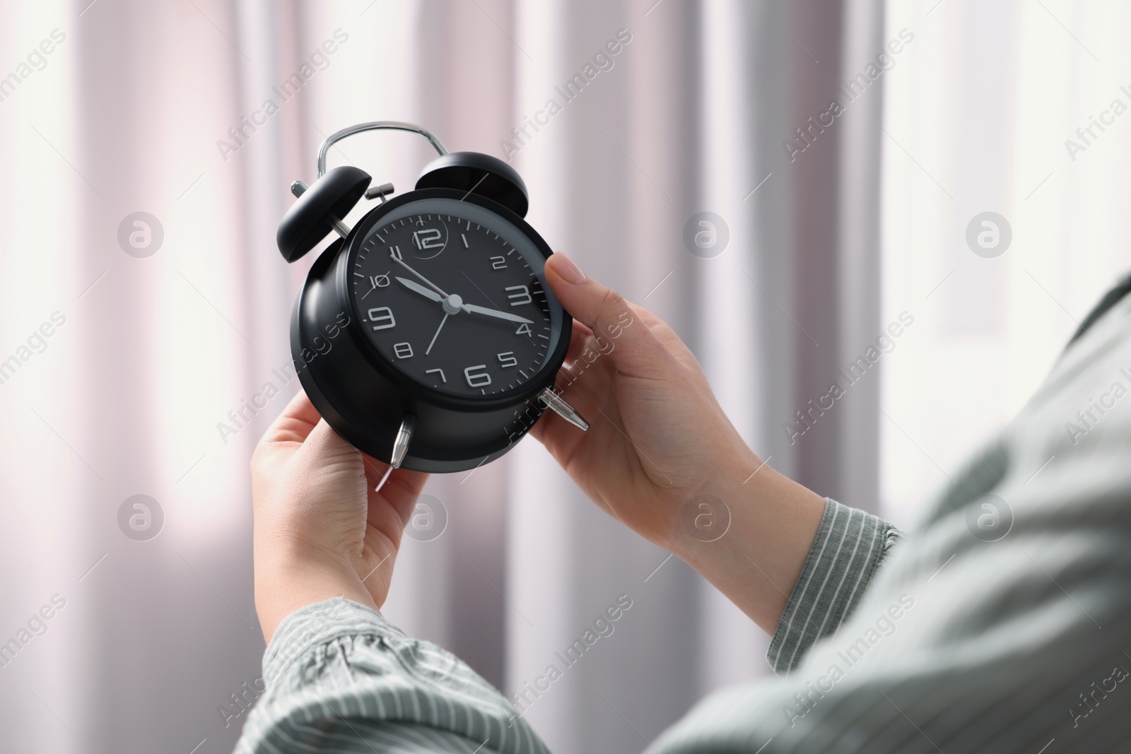 Photo of Woman with alarm clock indoors, closeup view