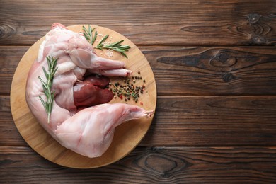 Photo of Whole raw rabbit, liver and spices on wooden table, top view. Space for text