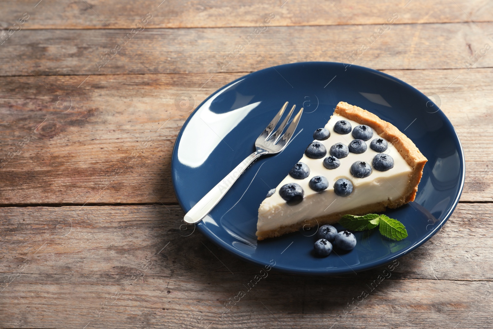 Photo of Plate with tasty blueberry cake on table. Space for text