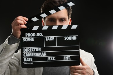 Adult actor holding clapperboard on black background