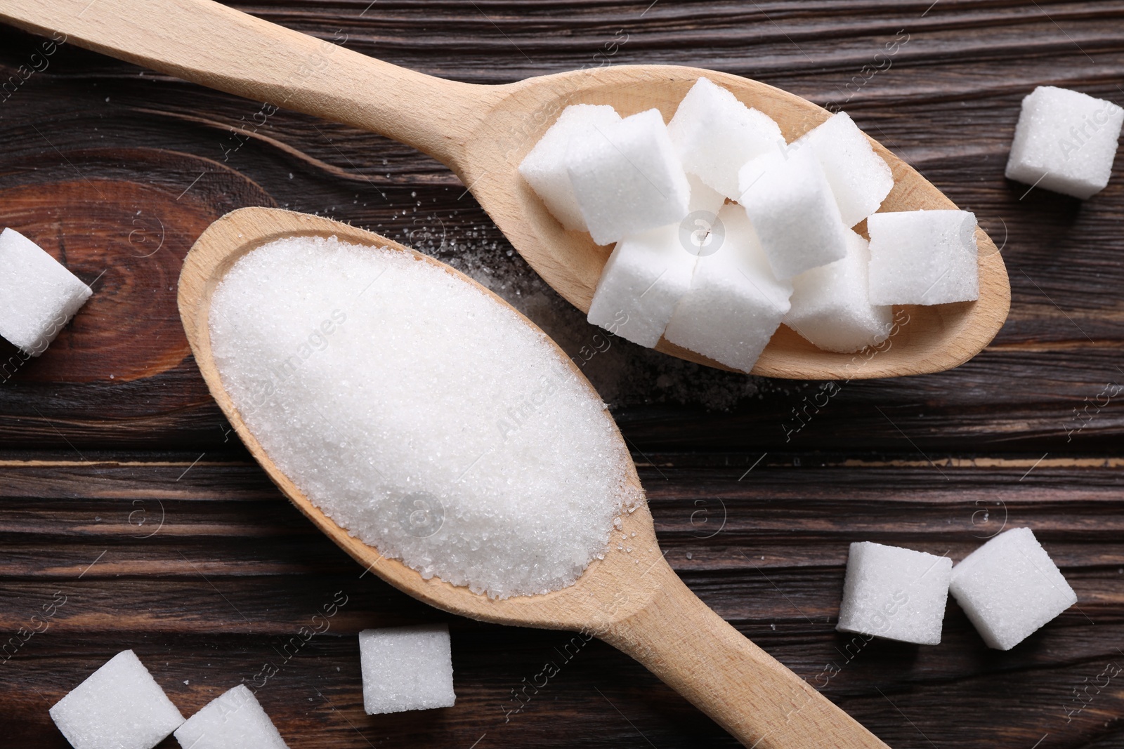 Photo of Spoons with different types of white sugar on wooden table, flat lay