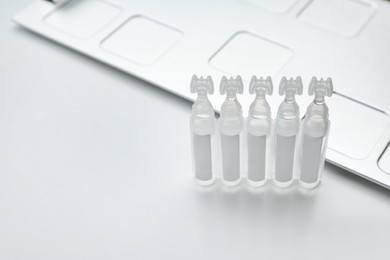Single dose ampoules of sterile isotonic sea water solution on white background. Space for text