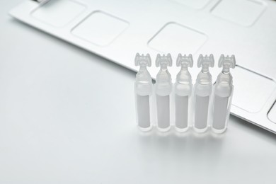 Photo of Single dose ampoules of sterile isotonic sea water solution on white background. Space for text