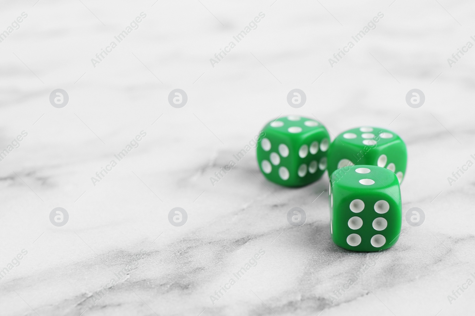 Photo of Three green game dices on white marble table. Space for text