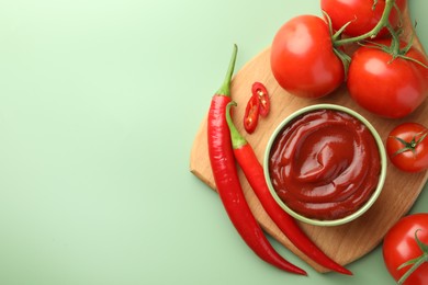 Photo of Bowl of tasty ketchup and ingredients on green table, top view. Space for text