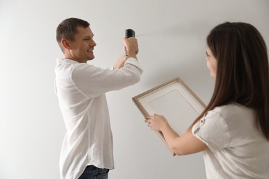 Photo of Couple decorating room with picture together. Interior design