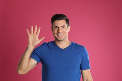 Photo of Man showing number five with his hand on pink background