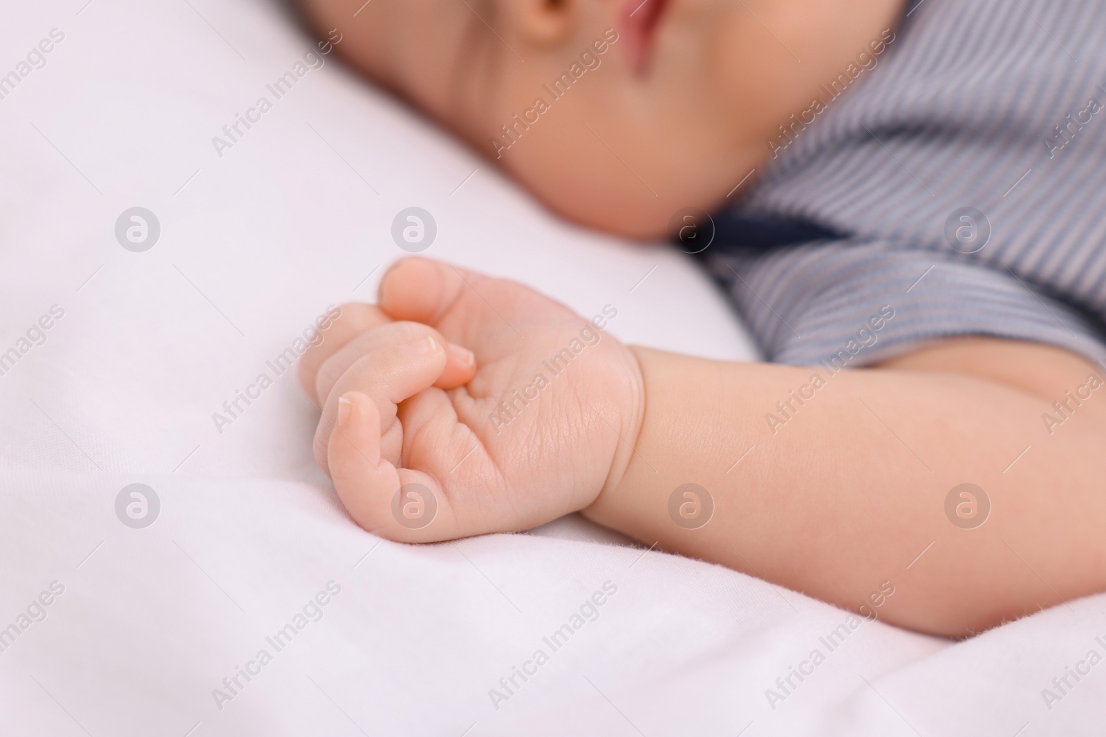 Photo of Newborn baby lying on white blanket, closeup