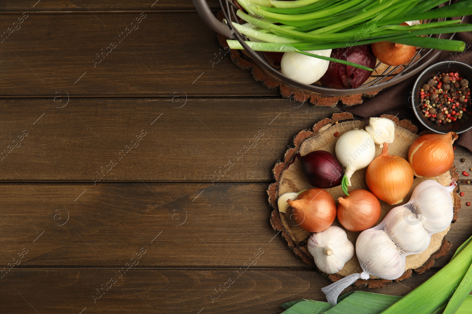 Photo of Fresh onion bulbs, leek and garlic on wooden table, flat lay. Space for text