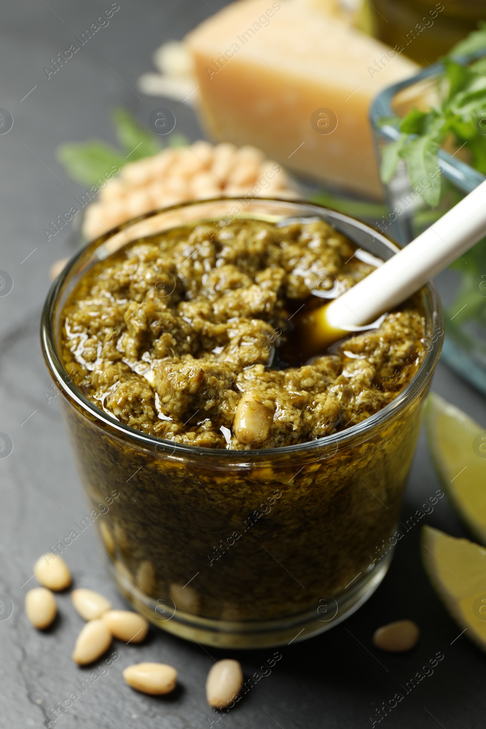 Photo of Glass of tasty arugula pesto on black table, closeup