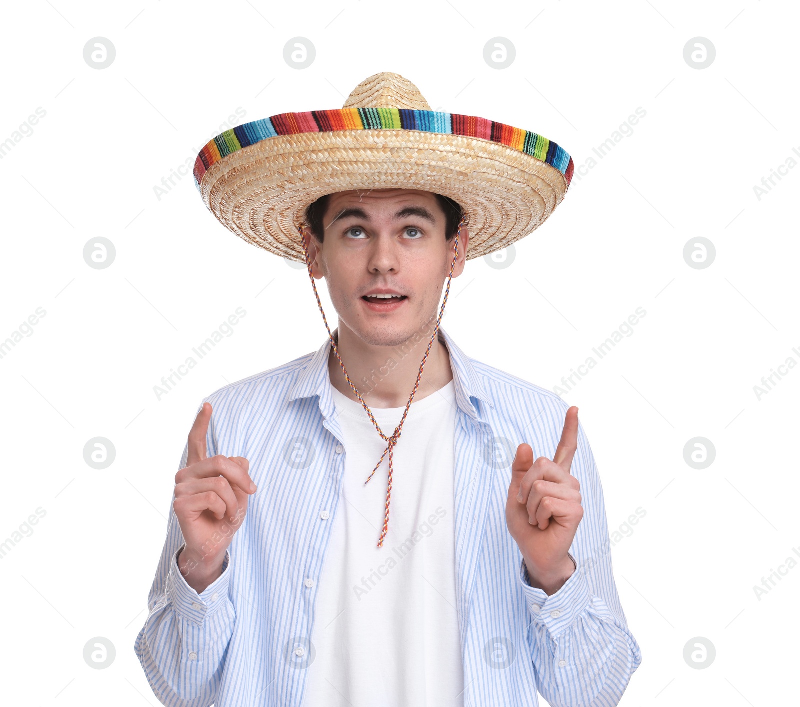 Photo of Young man in Mexican sombrero hat pointing at something on white background