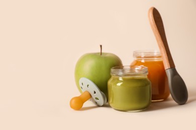 Photo of Healthy baby food, apple, pacifier and spoon on beige background. Space for text