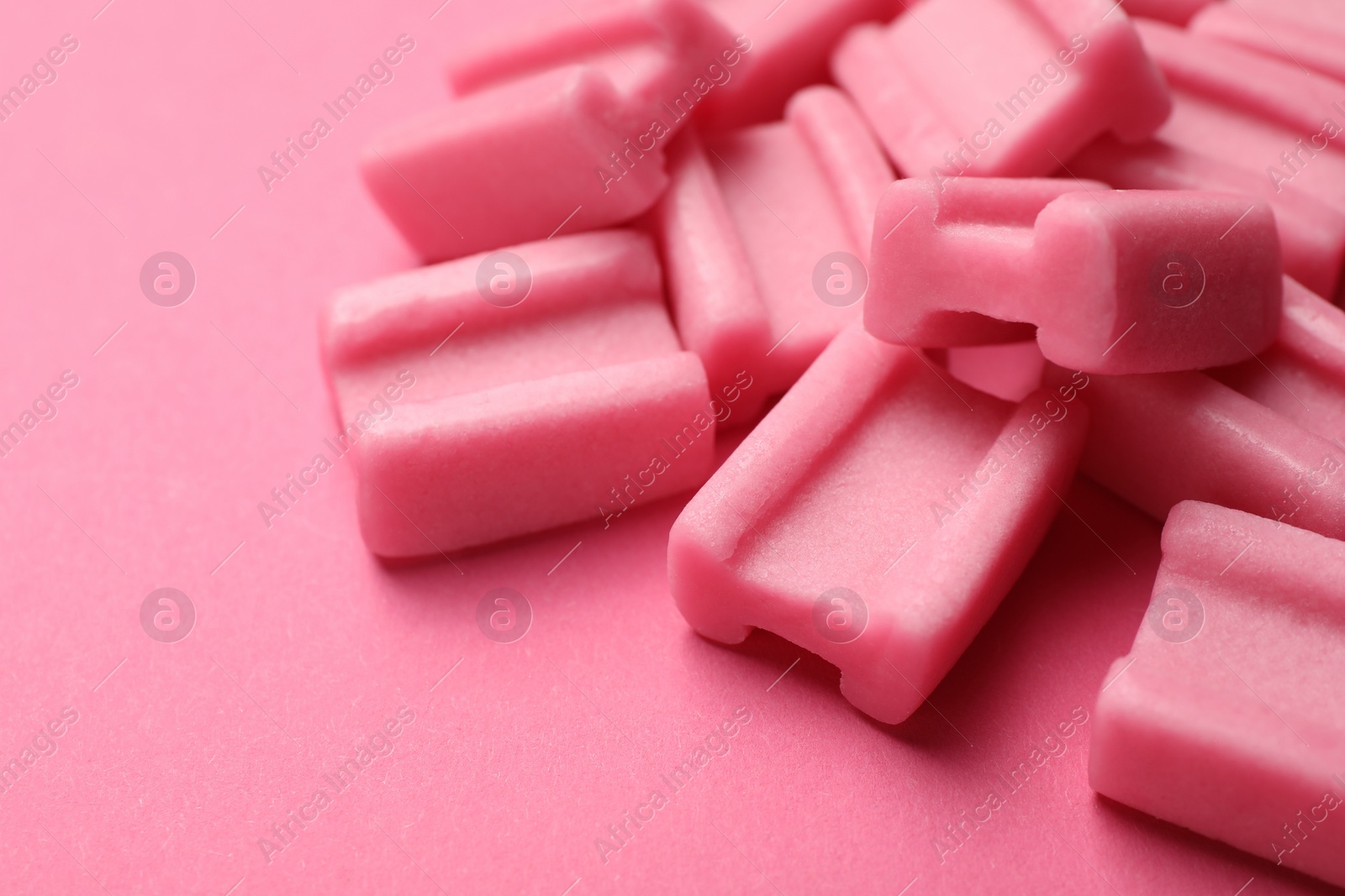 Photo of Tasty chewing gums on pink background, closeup