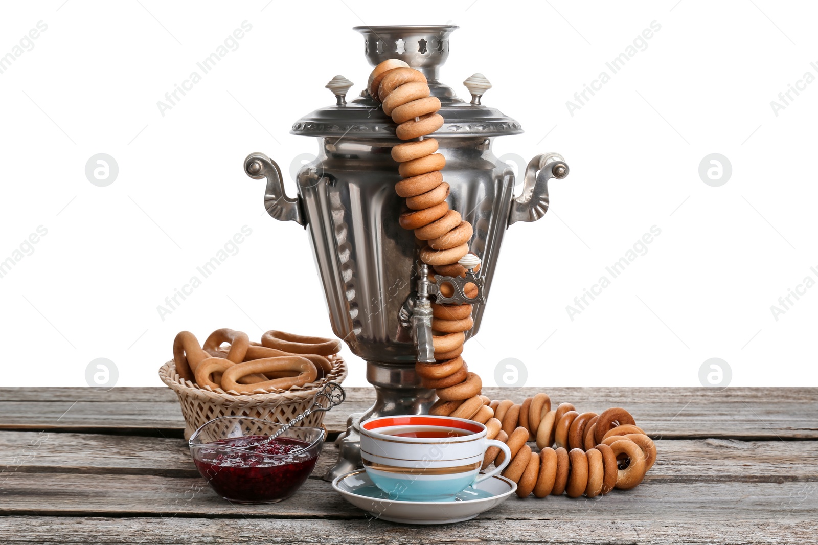 Photo of Samovar with hot tea, jam and delicious ring shaped Sushki (dry bagels) on table against white background