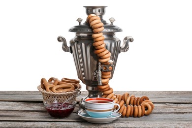 Photo of Samovar with hot tea, jam and delicious ring shaped Sushki (dry bagels) on table against white background