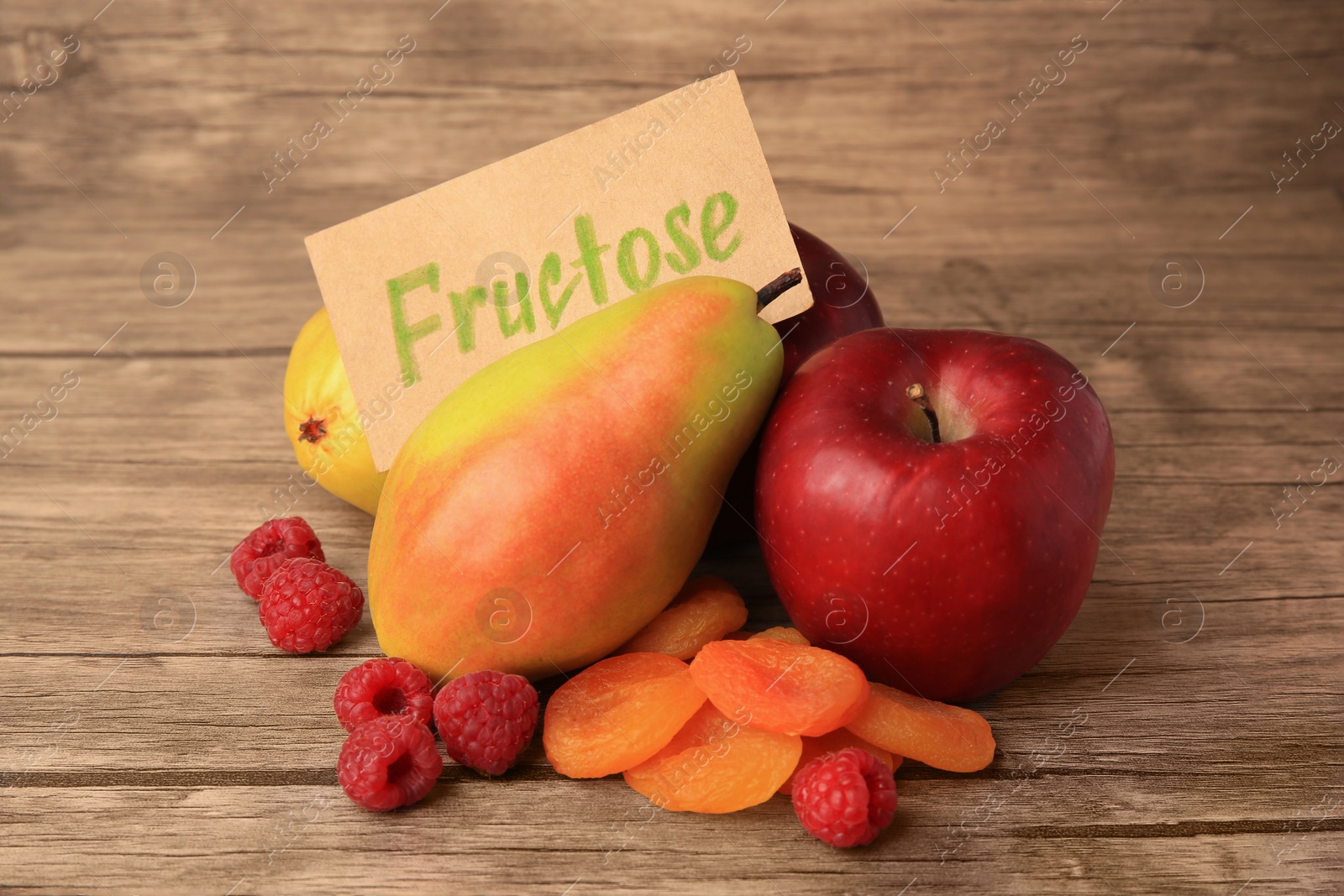 Photo of Card with word Fructose, delicious ripe fruits, raspberries and dried apricots on wooden table