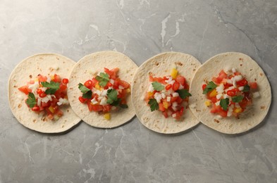 Photo of Delicious tacos with vegetables and parsley on grey marble table, top view