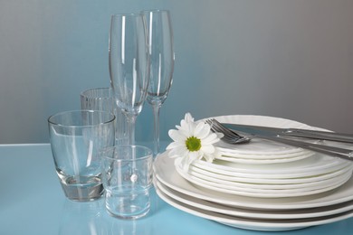 Photo of Set of clean dishes, glasses and cutlery on light blue table