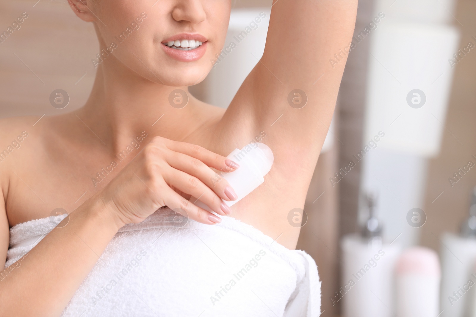 Photo of Beautiful young woman applying deodorant after shower in bathroom