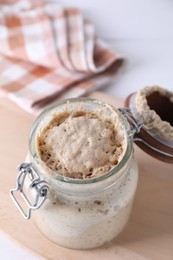 Photo of Sourdough starter in glass jar on table, closeup