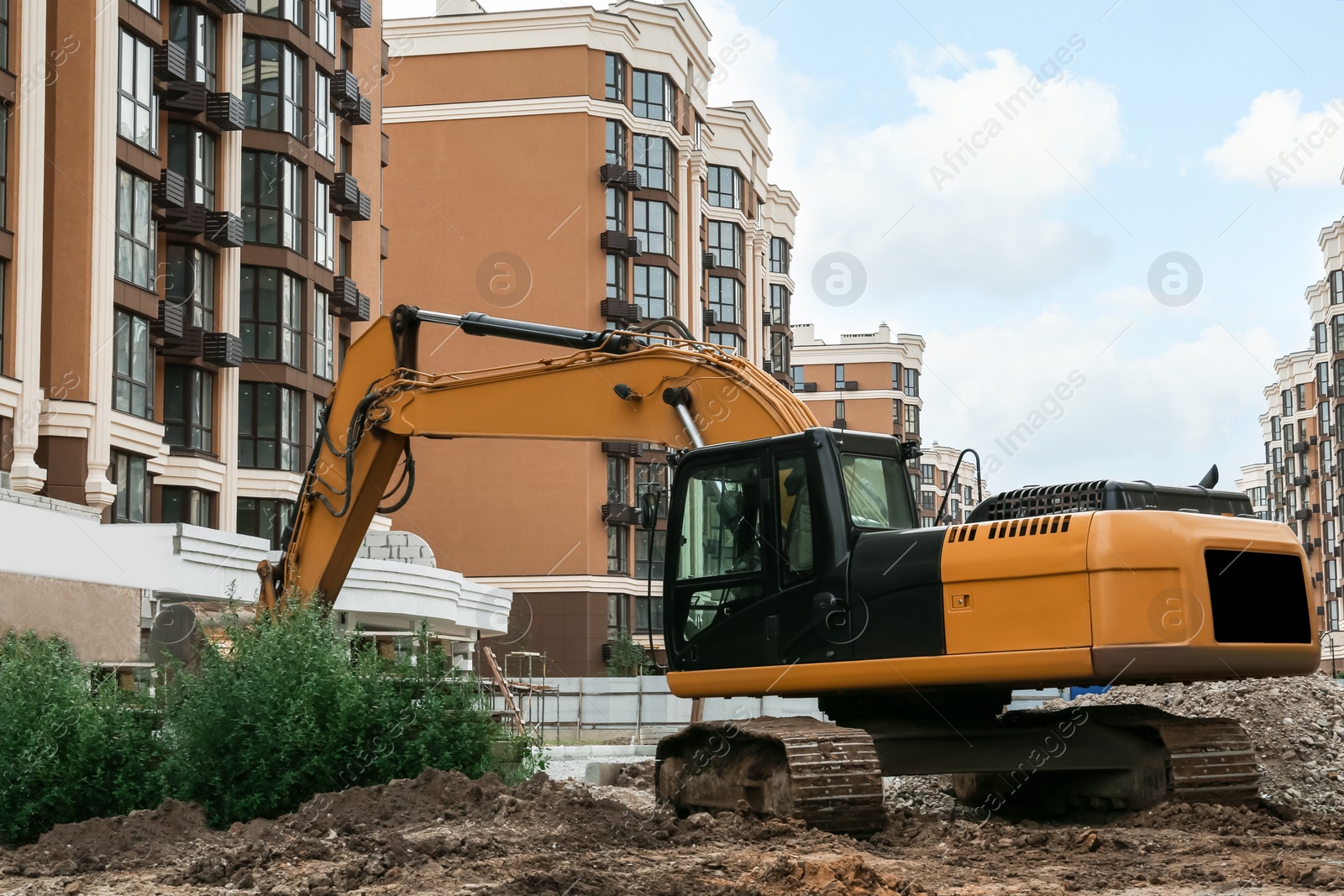 Photo of Modern excavator near buildings on construction site