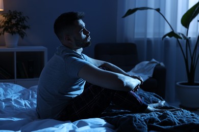 Frustrated man sitting on bed at night