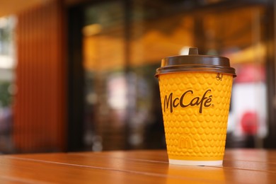 Photo of MYKOLAIV, UKRAINE - AUGUST 11, 2021: Hot McDonald's drink on table in cafe. Space for text