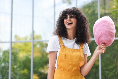 Photo of Smiling woman with cotton candy outdoors. Space for text