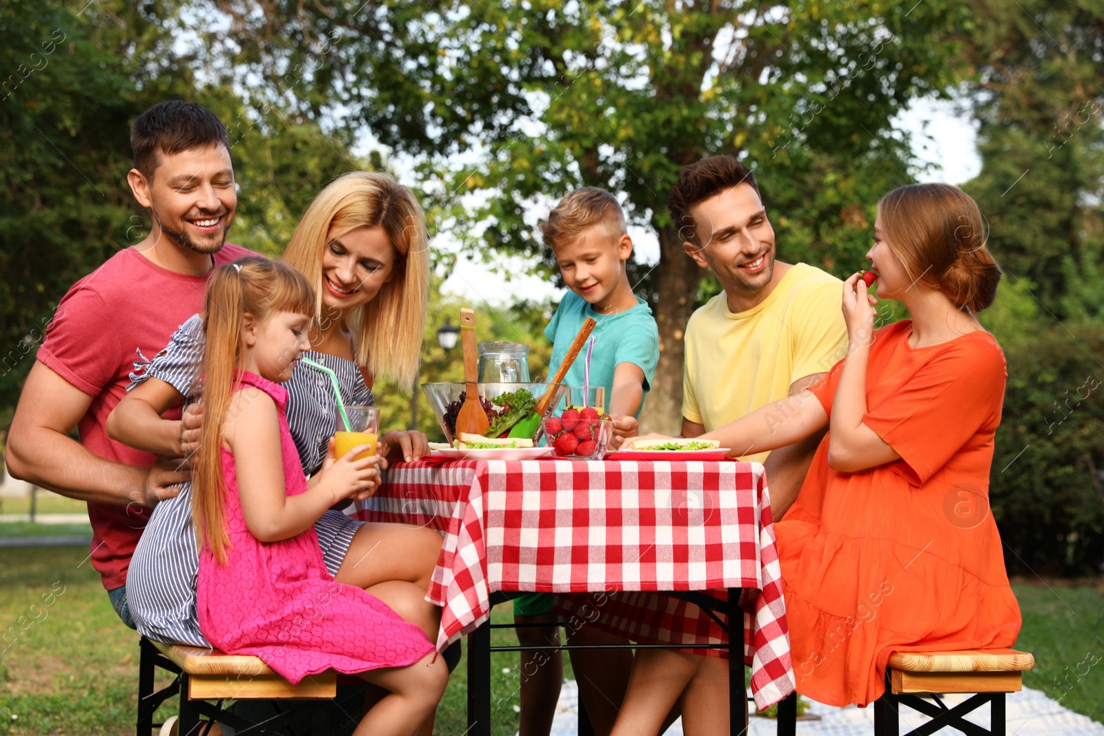 Photo of Happy families with children having picnic at table in park