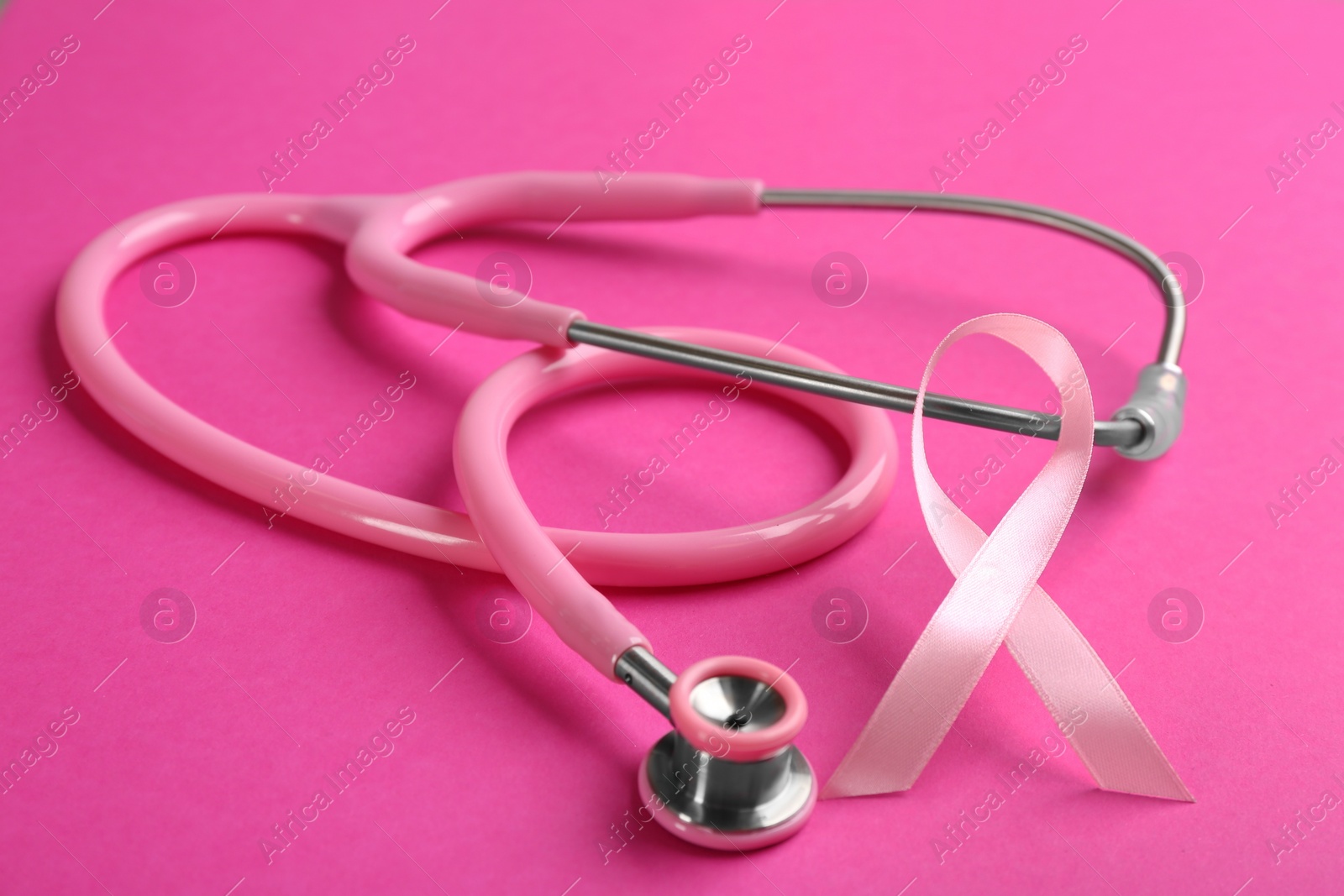 Photo of Pink ribbon and stethoscope on color background, closeup. Breast cancer concept