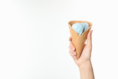 Woman holding delicious ice cream in waffle cone on white background, closeup