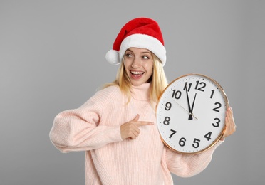 Photo of Woman in Santa hat with clock on grey background. New Year countdown