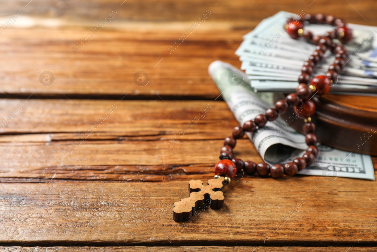 Photo of Cross and money on wooden table, closeup. Space for text