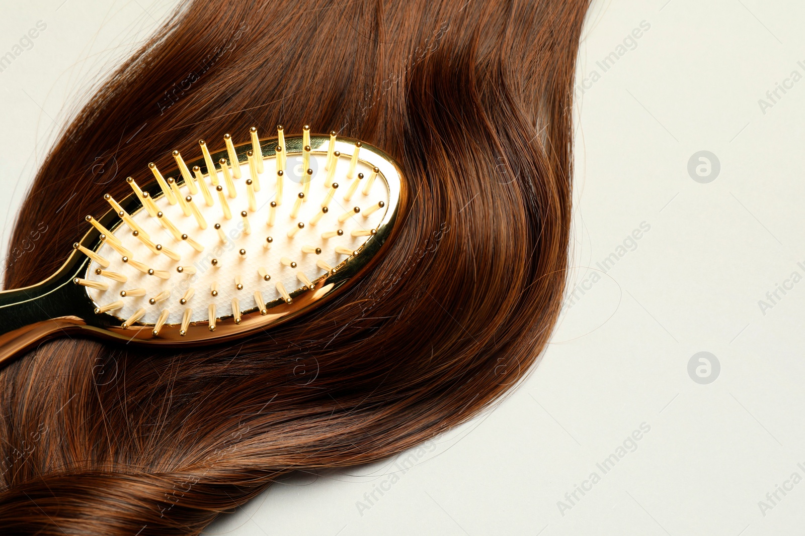 Photo of Stylish brush with brown hair strand on light grey background, top view