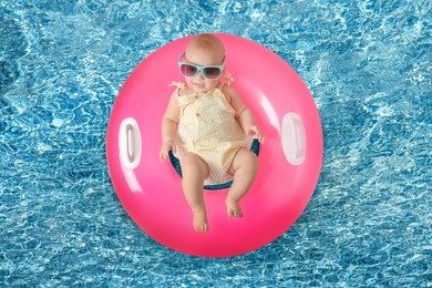 Cute little baby with inflatable ring in swimming pool, top view