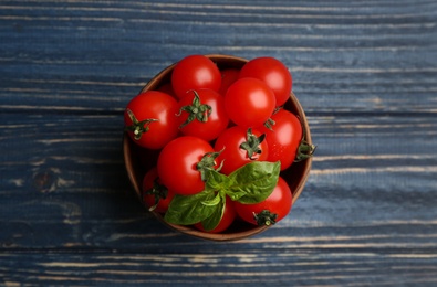 Photo of Fresh ripe cherry tomatoes and basil on blue wooden table, top view