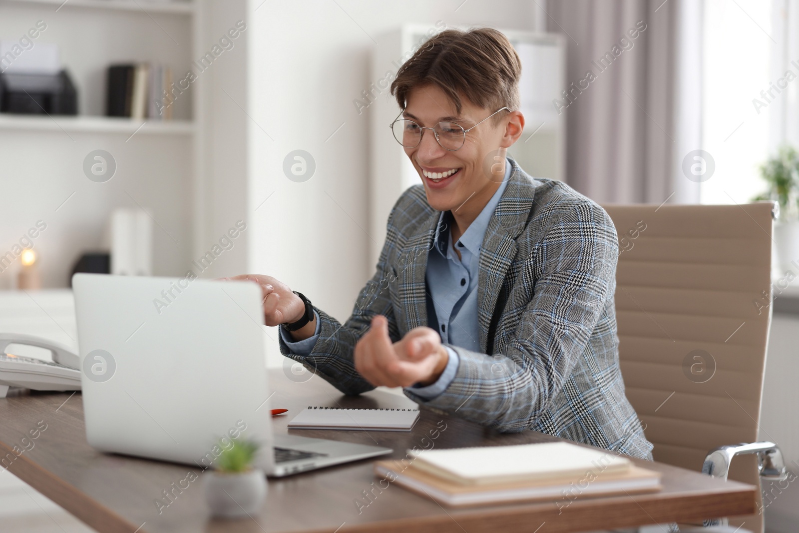 Photo of Man using video chat during webinar at wooden table in office