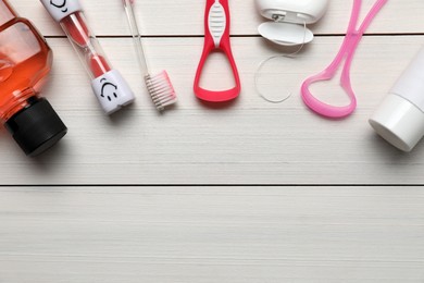 Photo of Flat lay composition with tongue cleaners and teeth care products on white wooden table, space for text