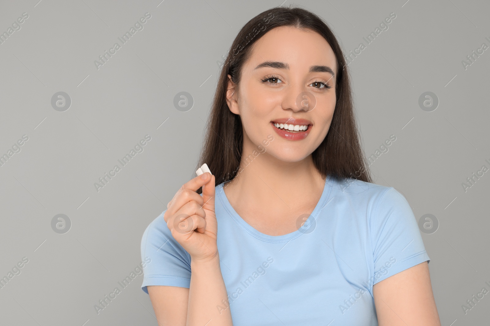 Photo of Happy young woman with bubble gums on grey background