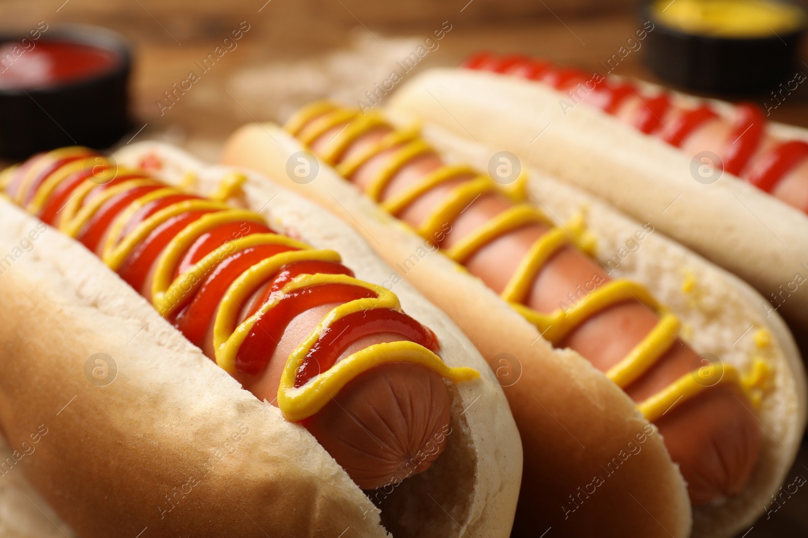 Photo of Delicious hot dogs with mustard and ketchup on table, closeup