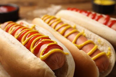 Photo of Delicious hot dogs with mustard and ketchup on table, closeup