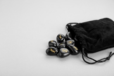 Photo of Bag with black rune stones on light grey background, space for text