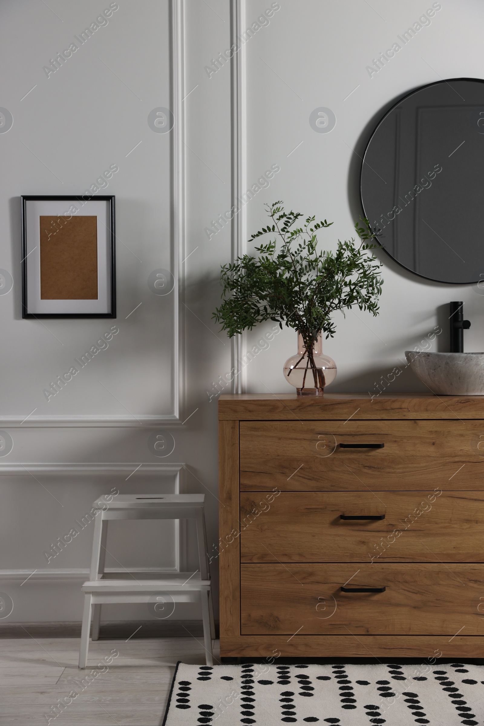 Photo of Modern bathroom interior with stylish mirror, eucalyptus branches, vessel sink and wooden vanity