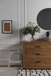 Photo of Modern bathroom interior with stylish mirror, eucalyptus branches, vessel sink and wooden vanity