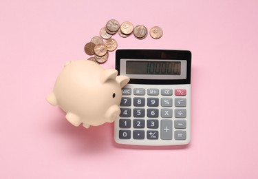 Calculator, coins and piggy bank on pink background, flat lay
