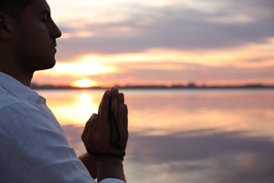 Man near river at sunset, space for text. Nature healing power