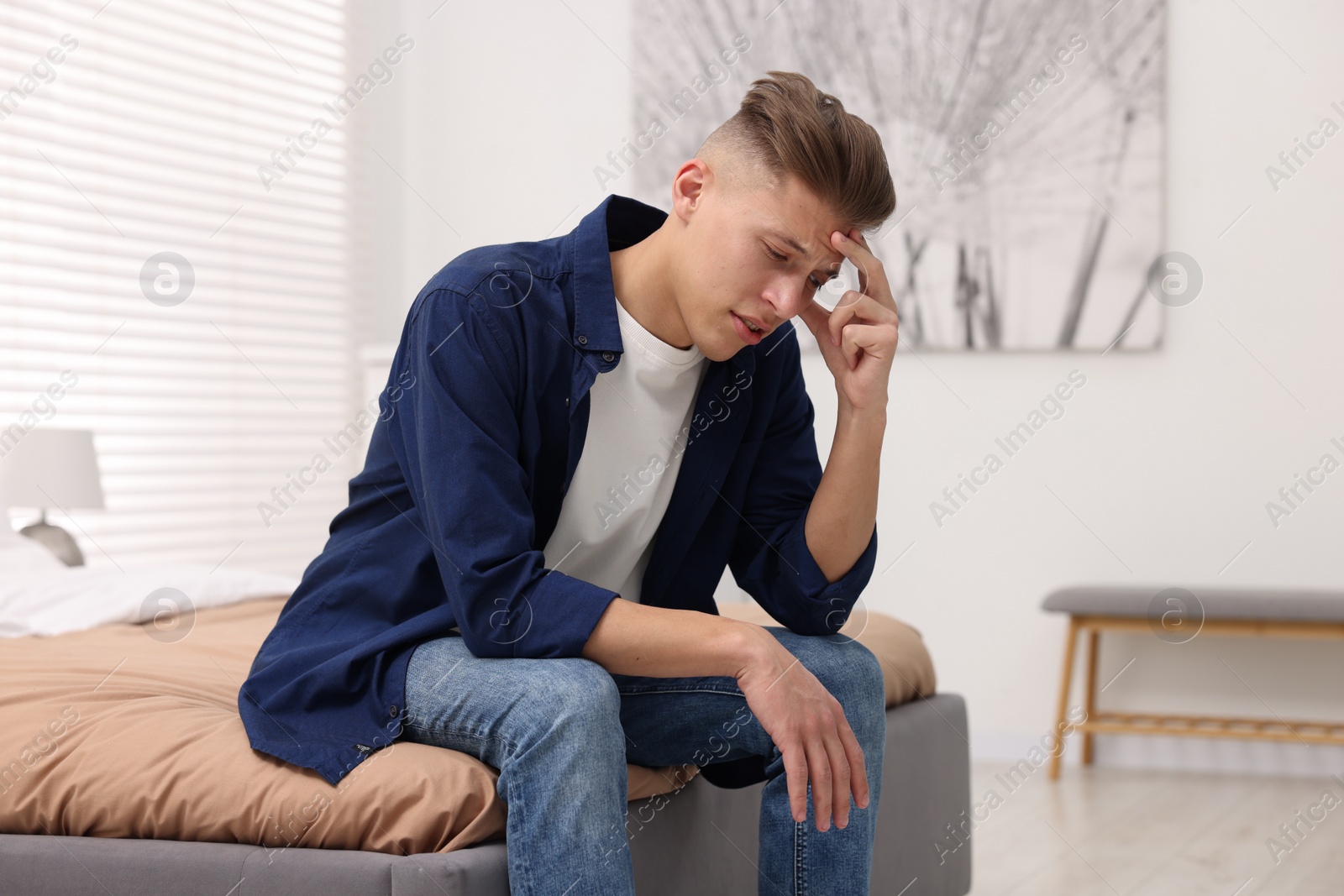 Photo of Overwhelmed man sitting on bed at home