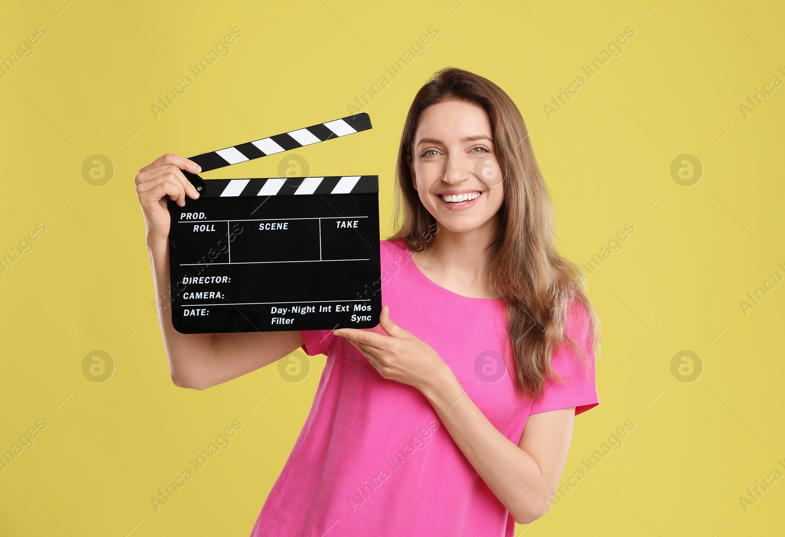 Photo of Making movie. Smiling woman with clapperboard on yellow background